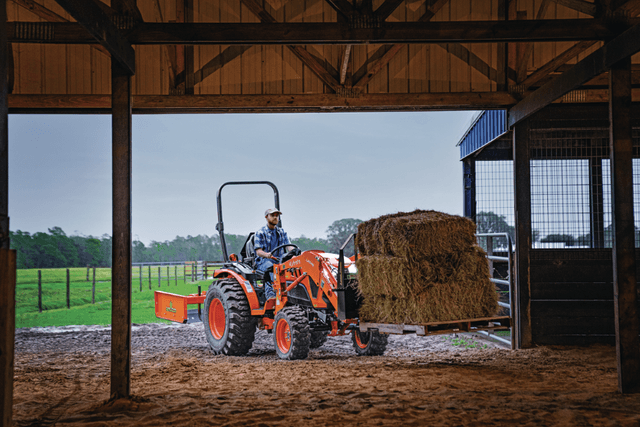 Man moving pallet of hay with tractor