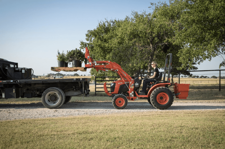 Woman using tractor to loads plants onto the rear of truck