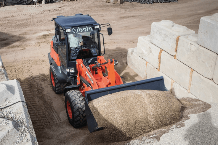 Man using wheel loader bucket to move gravel
