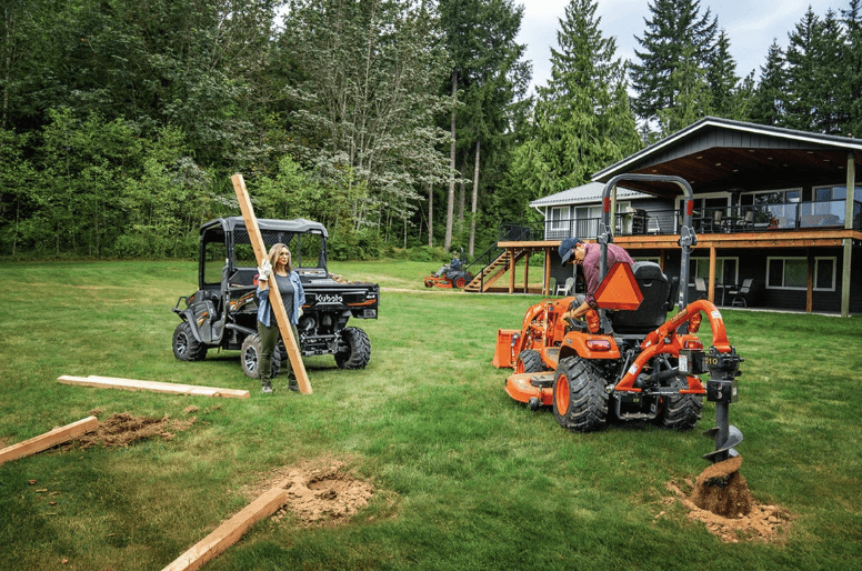 Man and woman using the Kubota utility vehicle and a Kubota tractor for a DIY project
