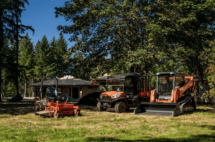 A lineup of a Kubota mower, utility vehicle, and track loader